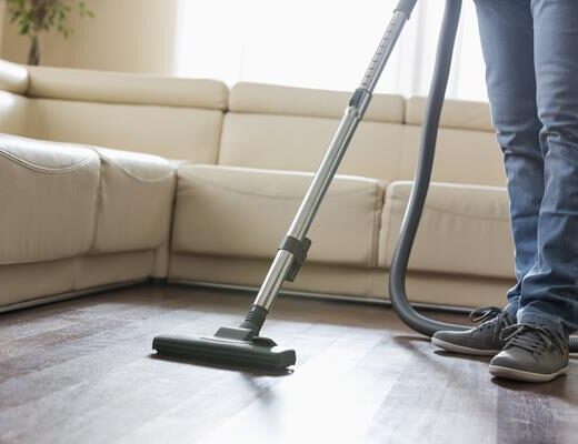 Low section of man cleaning hardwood floor with vacuum cleaner