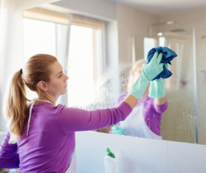 Kobieta myjąca lustro za pomocą domowej roboty płynu.